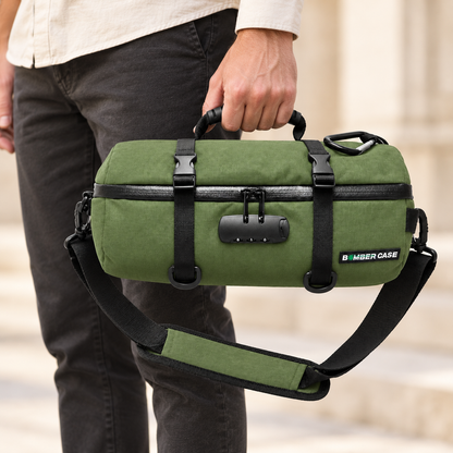 A hand carrying the compact green 14-inch Bomber Case duffle by its top handle.